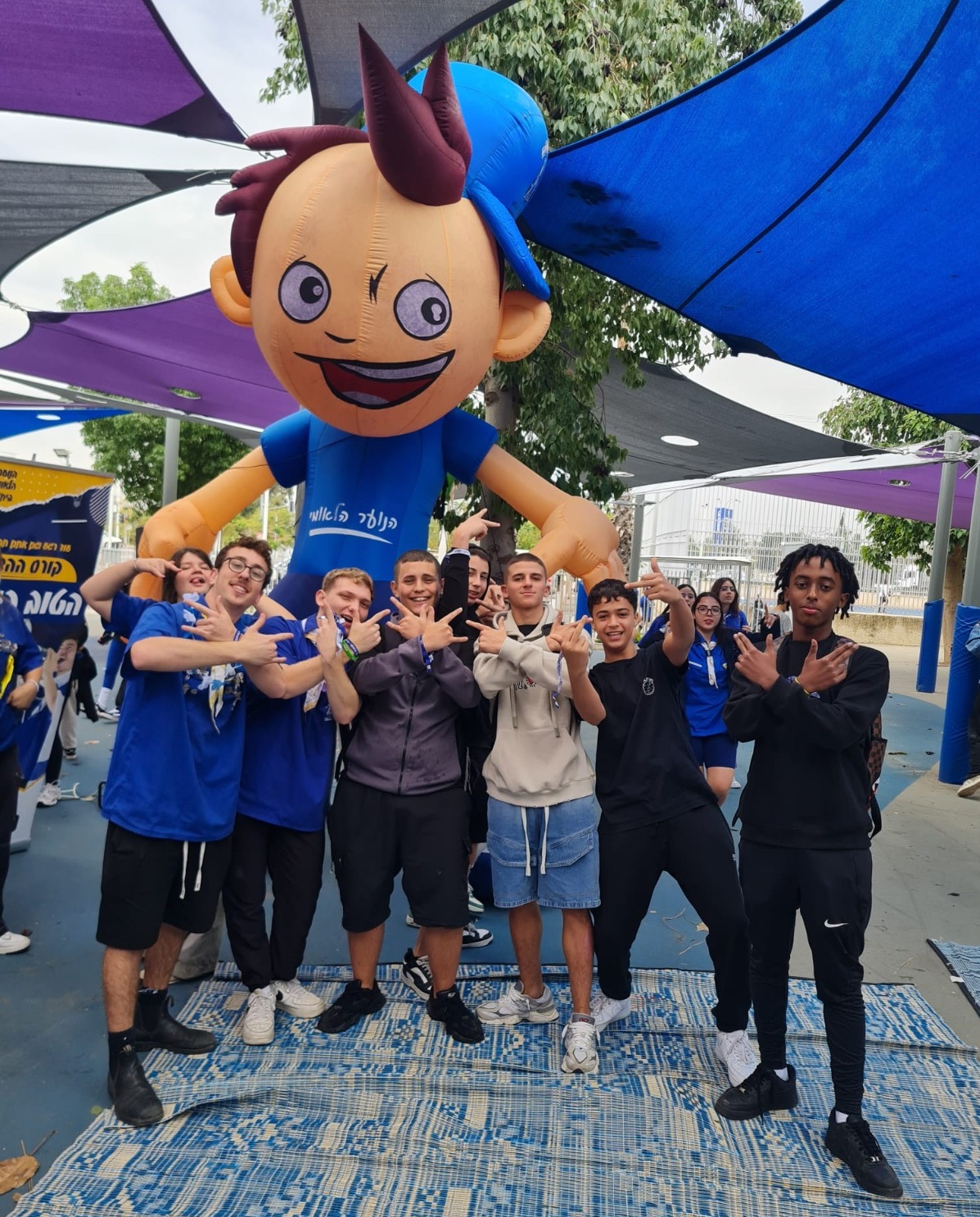 נערים ונערות בשנת שירות של הנוער הלאומי בית"ר ומאחוריהם בובת ענק