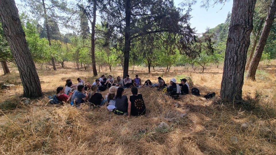נערים ונערות של ארגון לתת יושבים במעגל באמצע יער