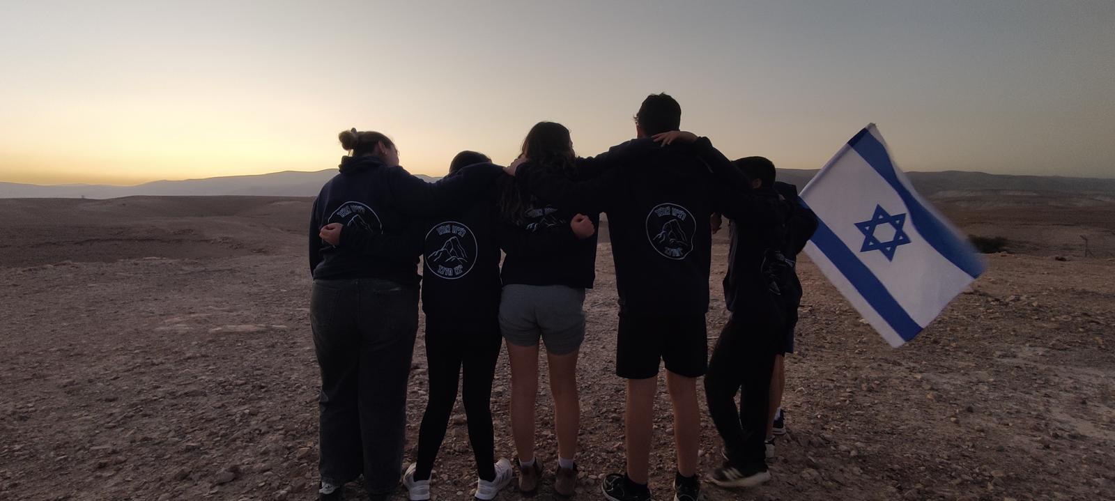 חבורה של בני נוער מצולמים מהגב לפנות ערב