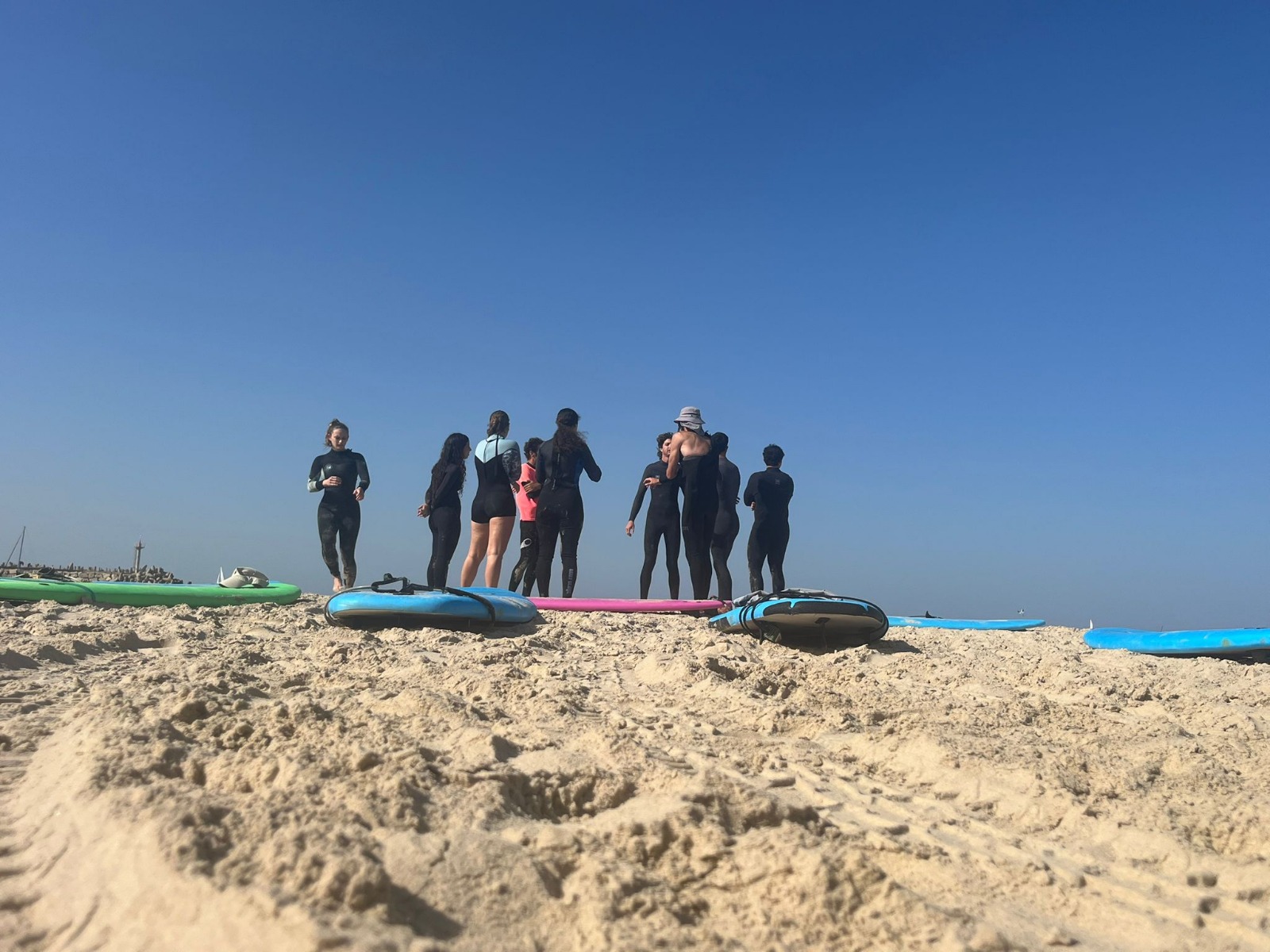 צעירים עם גלשנים על חוף ים מצולמים מרחוק