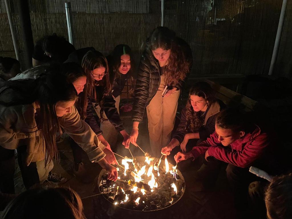 בני נוער יושבים סביב מדורה בלילה