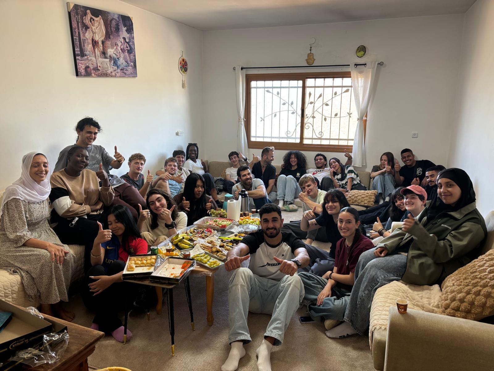 בני נוער ומבוגרים יושבים בצפיפות בסלון קטן