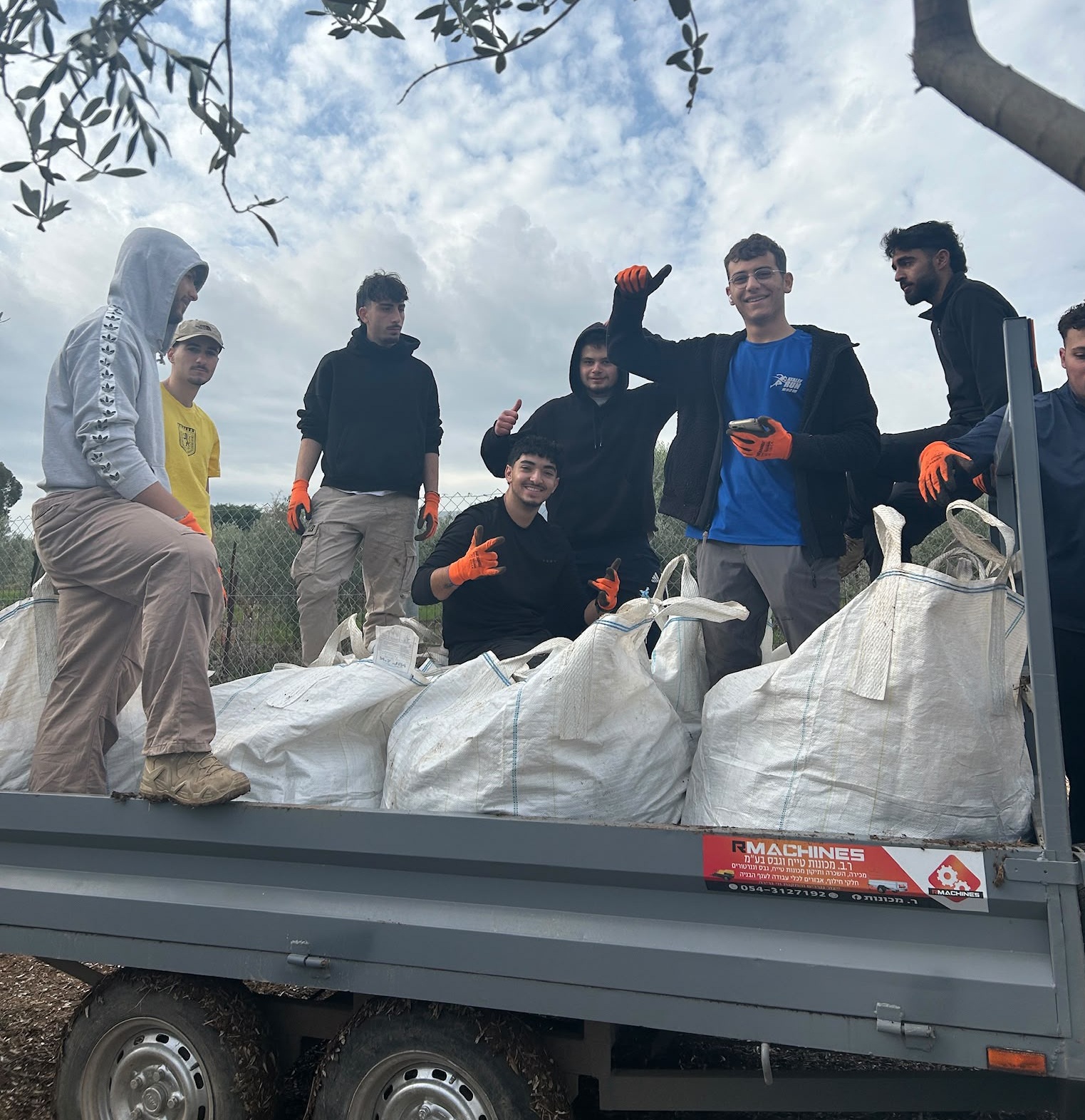 בני נוער עומדים על ארגש של משאית ולידם שקים גדולים