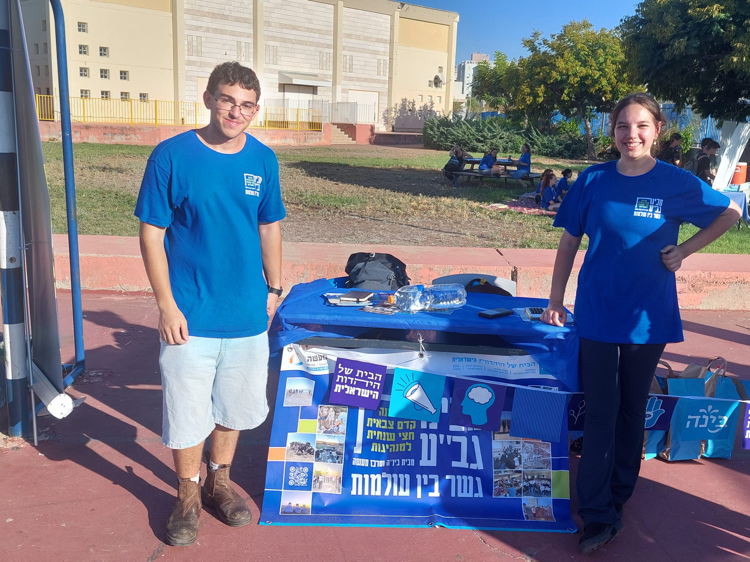 נער ונערה בחולצות כחולות משני צידי שולחן