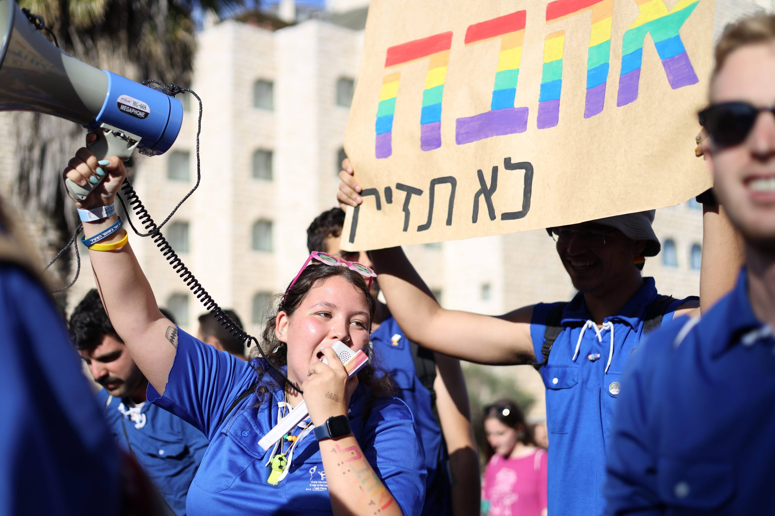 נערה בחולצה כחולה בהפגנה מחזיקה שלט